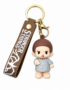 Stranger Things Eleven chibi PVC keychain wearing a grey hospital gown with a matching Stranger Things silicone wrist strap, gold-tone keyring, and lobster clasp on a white background.